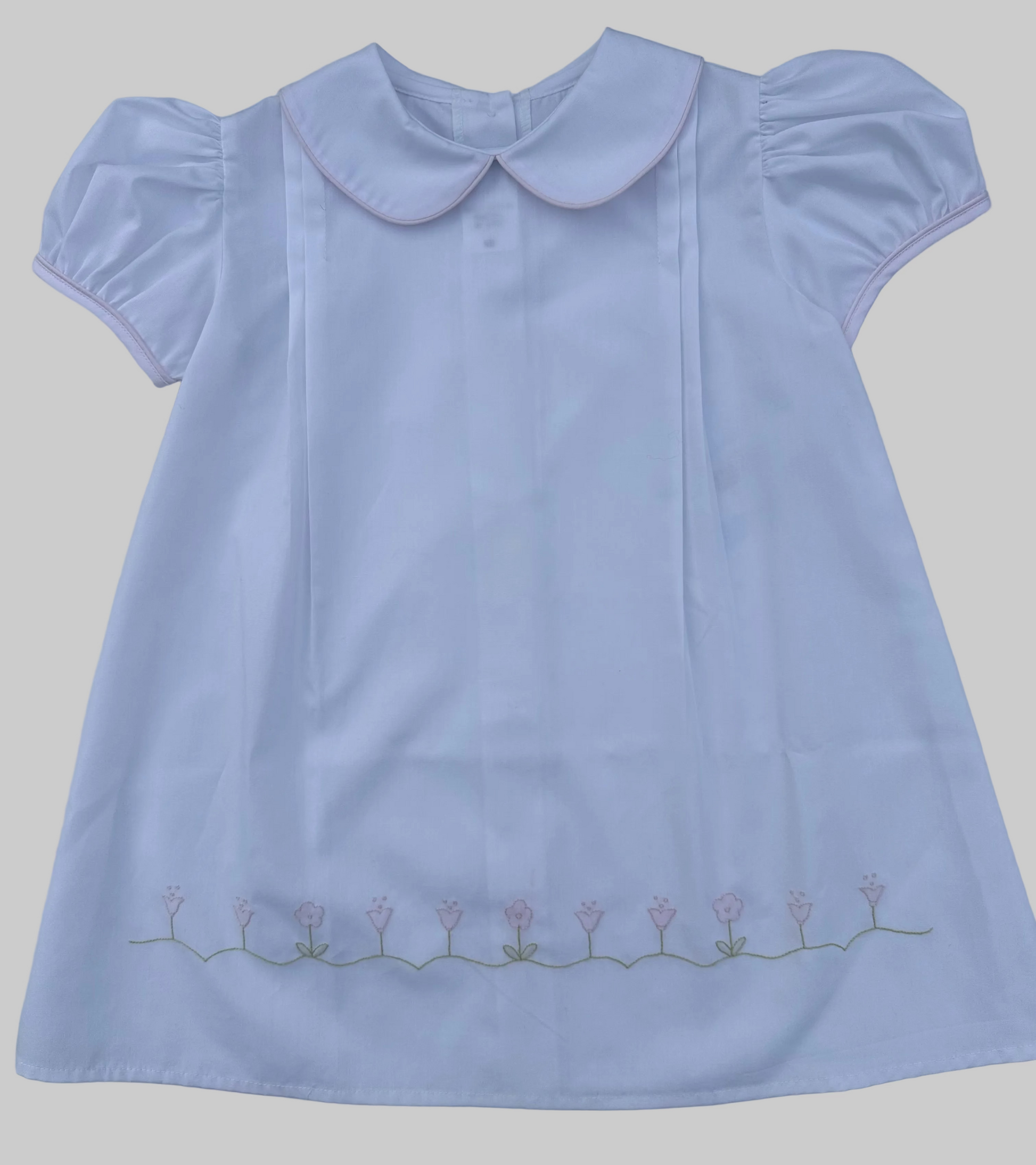 White dress with a Peter Pan collar and floral embroidery on a gray background
