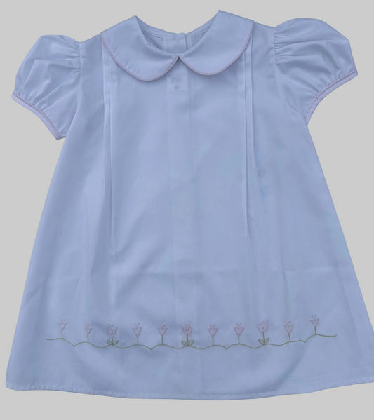 White dress with a Peter Pan collar and floral embroidery on a gray background